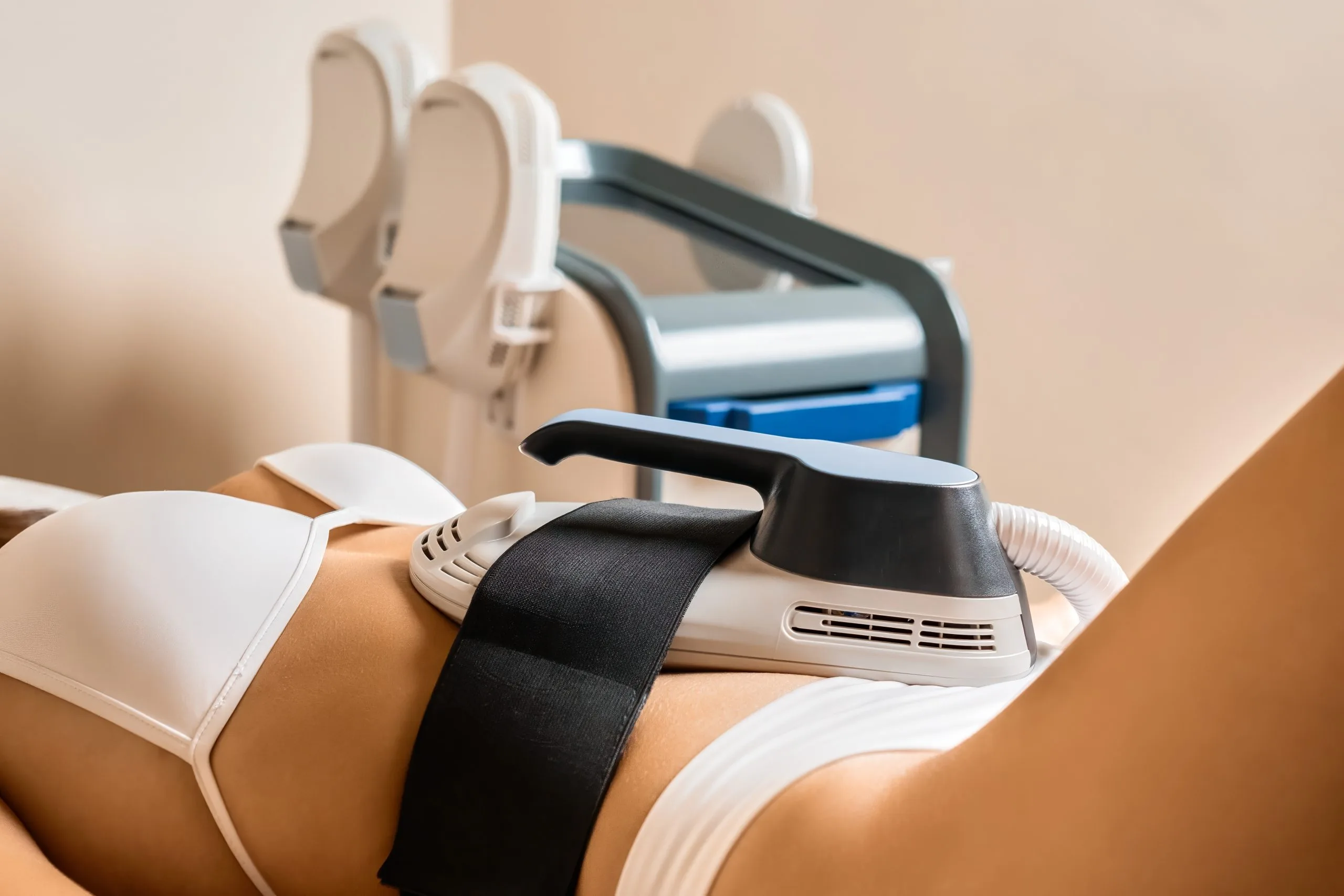 Clinician applying handheld radiofrequency device to patient's thigh during body contouring treatment
