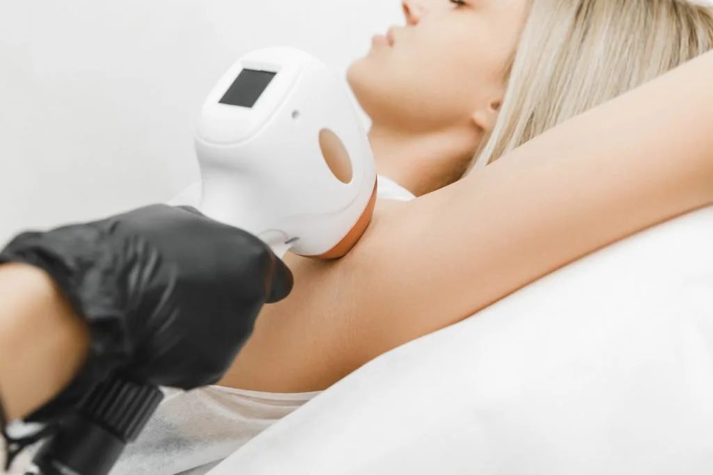 Provider applying handheld device to patient's arm during laser treatment