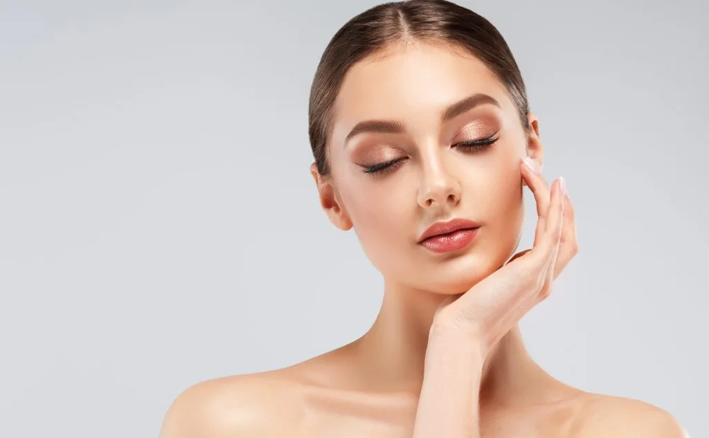 Woman with eyes closed touching her face with peaceful expression