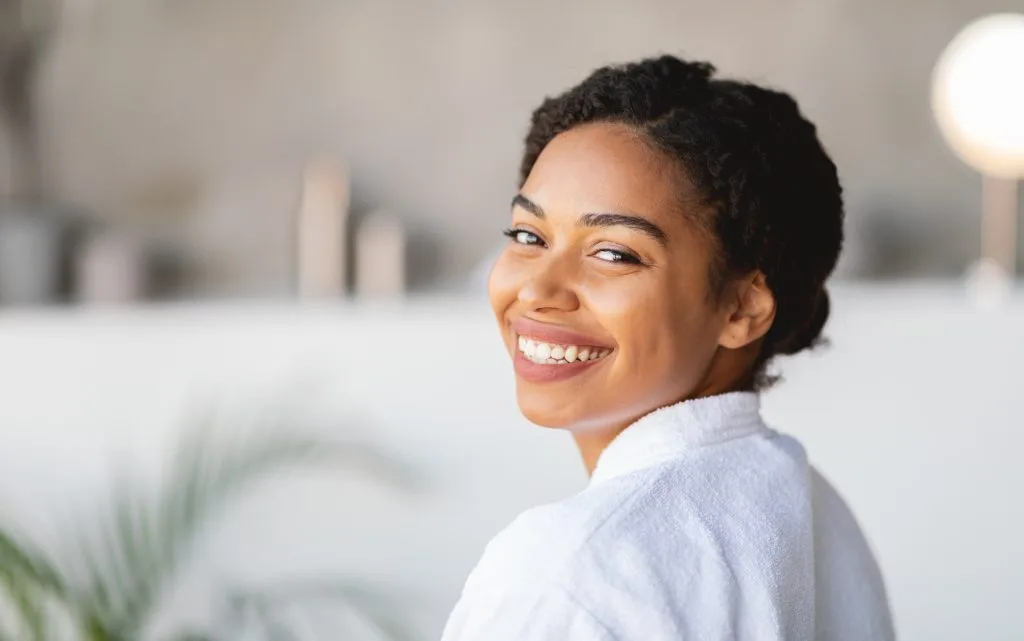 Woman in light blue shirt smiling at camera in bright indoor setting